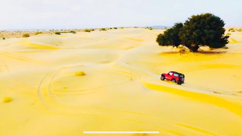 a red truck driving through the desert at DESERT OVERNIGHT LUXURY CAMP & ReSORT in Jaisalmer