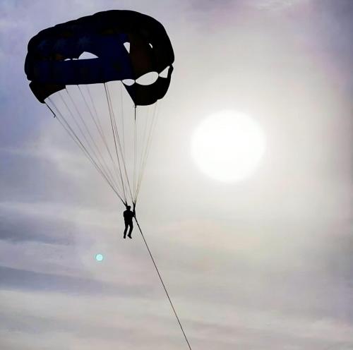 a person is parachuting with a batman parachute at DESERT OVERNIGHT LUXURY CAMP & ReSORT in Jaisalmer