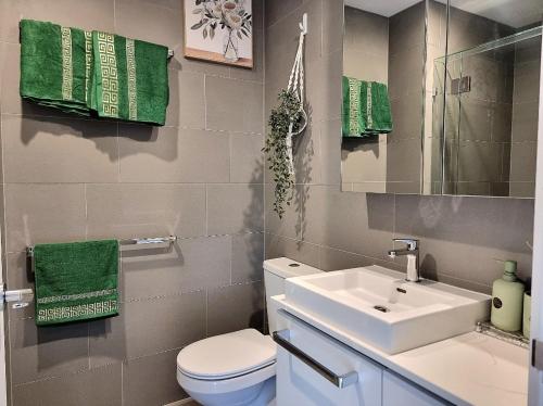 a bathroom with a sink and a toilet and green towels at Premium City Escape-Stunning Skyline Views in Brisbane