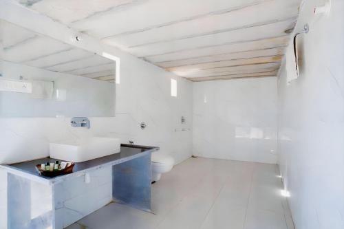 a white bathroom with a sink and a toilet at DESERT OVERNIGHT LUXURY CAMP & ReSORT in Jaisalmer