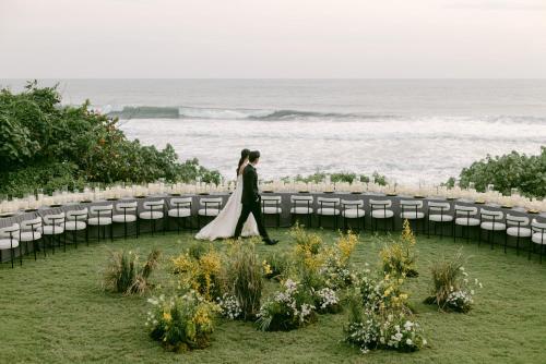 a bride walking down the aisle at a wedding by the ocean at Soori Bali in Tabanan
