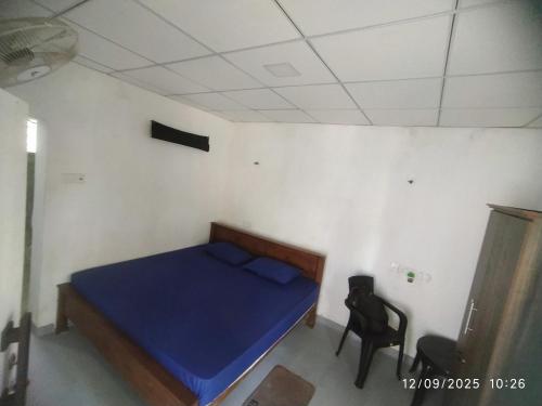 a small bedroom with a blue bed and a chair at Digital Nomads in Weligama