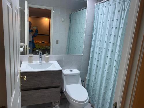 a bathroom with a toilet and a sink and a mirror at Departamento en Condominio Puerto Pacífico in Viña del Mar