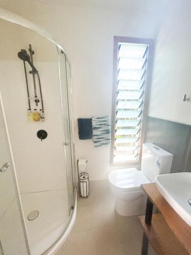 a bathroom with a toilet and a shower and a sink at Amori Cabin in Arorangi
