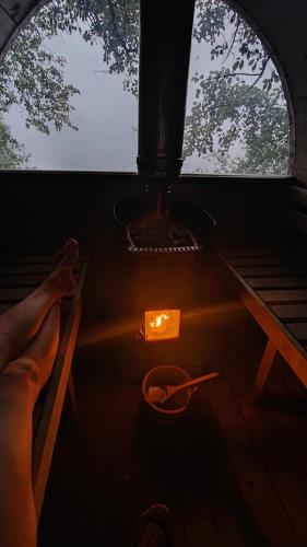 a persons feet on a table with a candle and a window at Naturlig på Korsgården Glamping in Nysted
