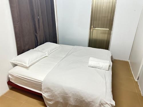 a bed with white sheets and pillows in a room at Green sea apartment in Nadi