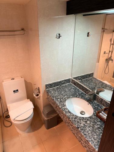 ein Badezimmer mit Waschbecken, Toilette und Spiegel in der Unterkunft Suncity Hotel Pattaya in Pattaya