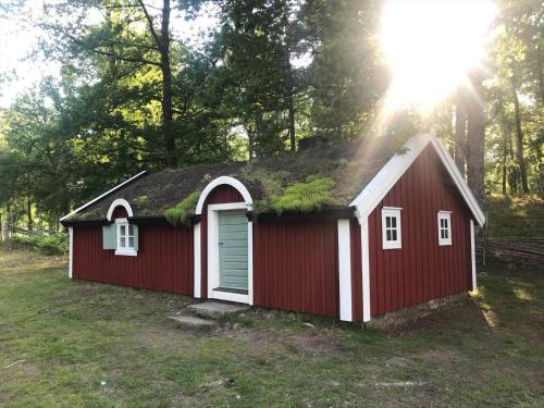 un capanno rosso con un tetto d'erba con il sole dietro di KRO073-Tingsryd-Groenvik-5 a Siggamåla