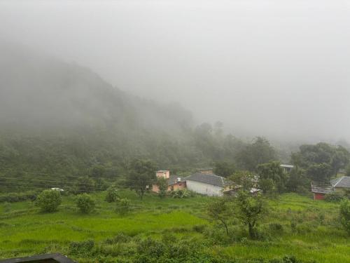 Un campo brumoso con casas en medio de una montaña en Serene Stay Baijnath, en Sahel