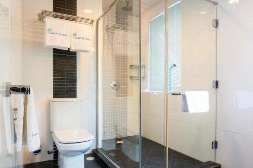 a bathroom with a toilet and a glass shower at Plaza Sutera Biru Hotel in Kuala Belait