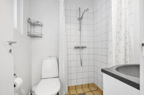 a white bathroom with a toilet and a shower at 5579-Gudhjem-Sdr-Strandvej-128-1-lejl-17 in Gudhjem