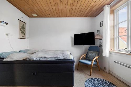 a bedroom with a bed and a chair and a television at 5644-Gudhjem-Holkavej-13-B in Gudhjem