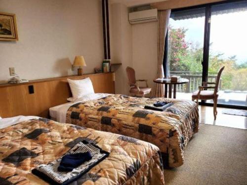 a hotel room with two beds and a balcony at Kirishima Onsen Ryokojin Sanso in Kirishima