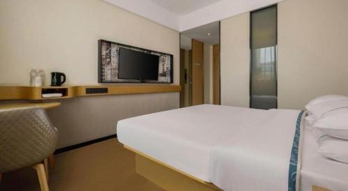 a bedroom with a white bed and a tv on the wall at City Comfort Inn Liuzhou Wuling Liutai Road in Liuzhou