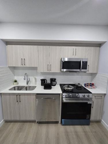 a kitchen with a stove and a sink and a microwave at Peaceful Haven in Prime Location in Calgary