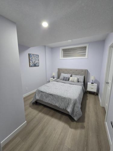 a bedroom with a bed in a white room at Peaceful Haven in Prime Location in Calgary