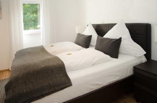 a bed with white pillows and a gray blanket at Apart Hotel Paradies in Bad Salzschlirf