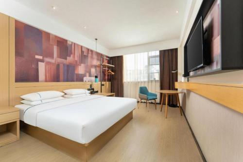 a hotel room with a bed and a flat screen tv at City Comfort Inn Shiyan Wudang Mountain in Danjiangkou