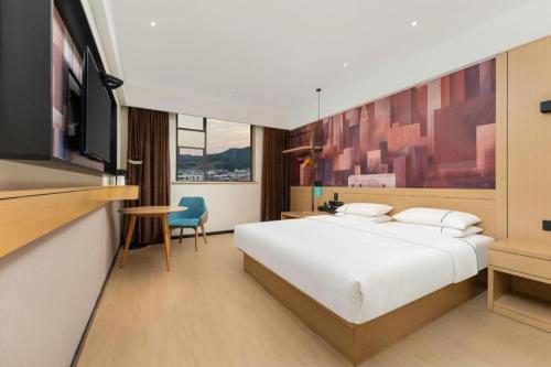 a hotel room with a bed and a flat screen tv at City Comfort Inn Shiyan Wudang Mountain in Danjiangkou
