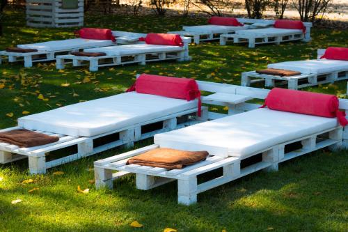a group of white benches with red cushions on the grass at Hotel Balneario Valle del Jerte in Valdastillas
