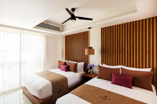 two beds in a hotel room with a ceiling fan at Kadun Hotel Boutique in Cabo San Lucas