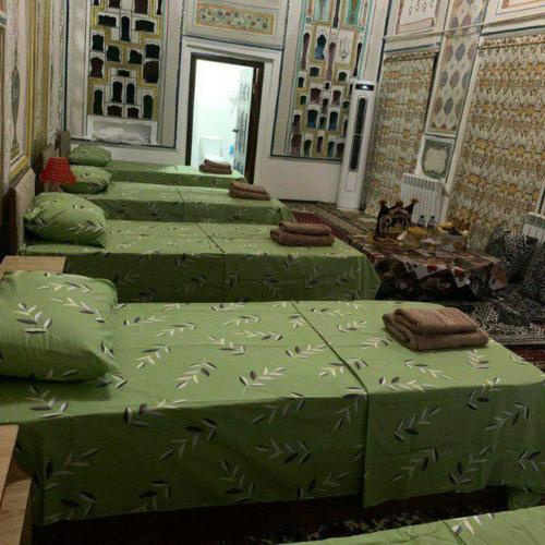 een rij groene bedden in een kamer bij Mekhtarin in Bukhara