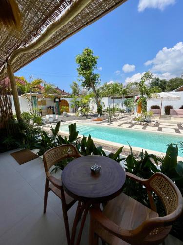 a patio with a table and chairs and a pool at Alma Nusa Penida in Nusa Penida