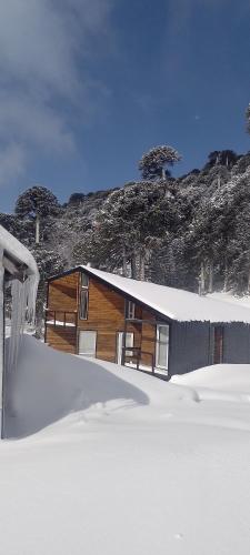 a house in the snow in front of a mountain at Peumañanku sueño de aguila in Lonquimay