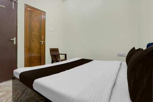 a bedroom with a bed and a wooden door and a chair at SPOT ON Rajshree Homestay Varanasi in Varanasi