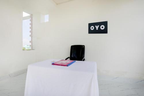 a table with a white table cloth and a sign on a wall at SPOT ON Hotel Chandi in Bihār Sharīf