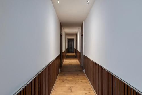 a corridor in an office building with white walls and wooden floors at Hotel O The Faam in Rajkot