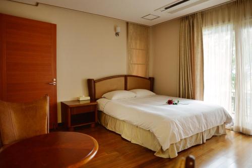 a bedroom with a bed with a table and a window at Minitel Soul in Seogwipo