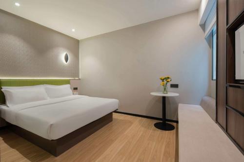 a bedroom with a bed and a vase of flowers on a table at Rezen Select Hotel (Guangzhou Keyun Road Financial City) in Guangzhou