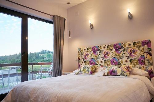 una camera da letto con un letto grande e una grande finestra di A Carballeira do Tambre a Troitosende