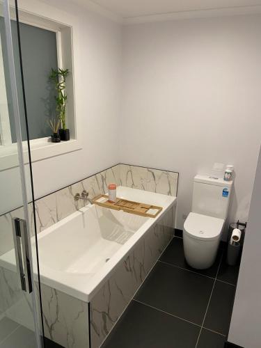 a bathroom with a tub and a toilet at The Johnsonville Lookout - Bed & Breakfast in Wellington