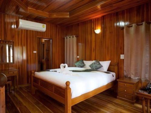 una camera da letto con un grande letto e pareti in legno di Srisawat Resort a Hua Hin
