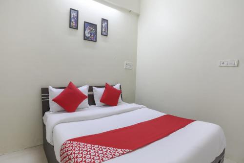 a bedroom with a bed with red and white pillows at Hotel O Shyam Vatika Banquet And Rooms in Surat