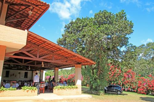 a patio with awning and a tree with flowers at Pousada Gruta in Ubajara