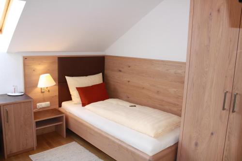 a small bedroom with a bed with a wooden headboard at Bäckerei Konditorei Frühstückspension WAGNER in Hutthurm