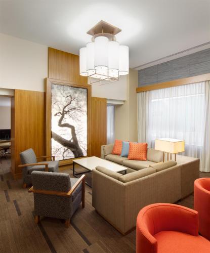a living room with couches and chairs and a chandelier at Hyatt Place Denver Cherry Creek in Denver