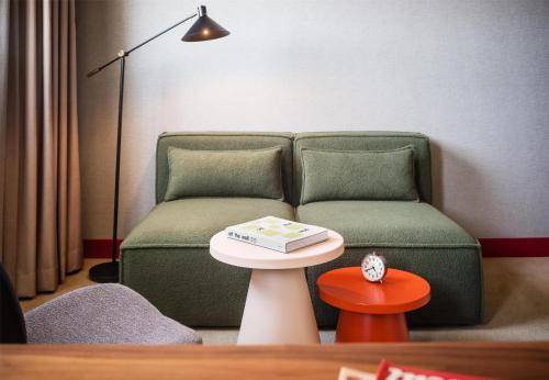 a living room with a couch and a table with a book on it at Me and All Hotel Berlin East Side, by Hyatt - NEW OPENING in Berlin