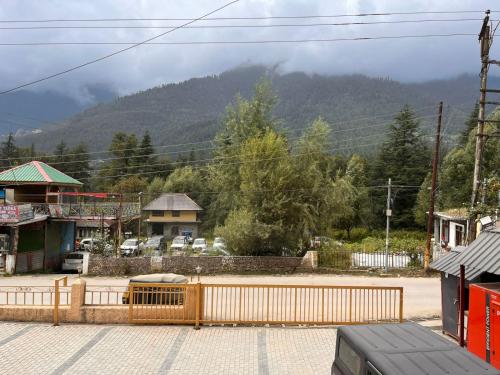 a town with a fence and a mountain in the background at Mountain Paradise in Dharamshala
