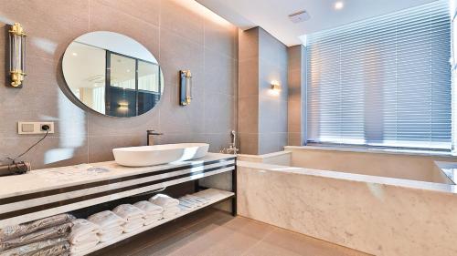 a bathroom with a sink and a tub and a mirror at Shire Hotel Seomyeon in Busan