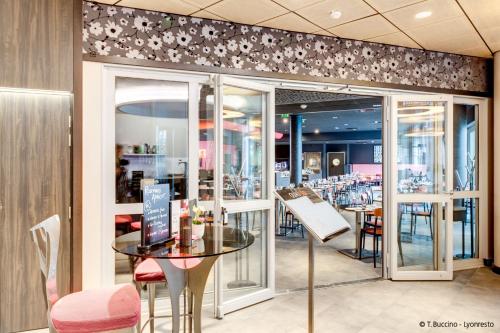 uma sala de jantar com mesa e cadeiras e um restaurante em Hotel Lyon-ouest em Lyon