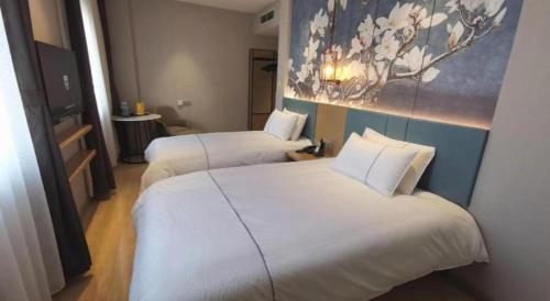 two beds in a hotel room with a painting on the wall at Jinjiang Inn Tianjin Station Jinwan Square in Tianjin