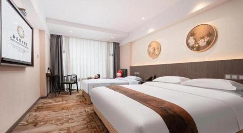 a hotel room with two beds and a flat screen tv at New Friendship Hotel in Luoyang