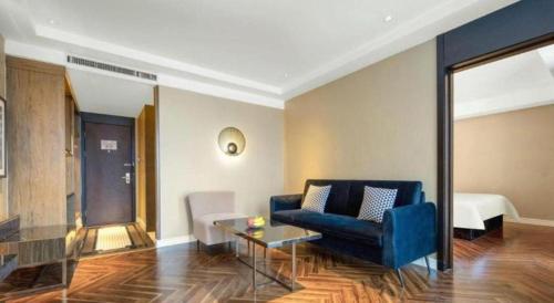 a living room with a blue couch and a table at Jinjiang Metropolo Hotel - Taizhou Wanda Plaza in Taizhou
