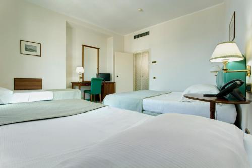 a hotel room with three beds and a desk at Lloyd's Baia Hotel in Vietri sul Mare