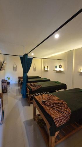 a room with three beds in it with blue curtains at Abian Klumpu Villa & Spa Sanur Bali in Sanur