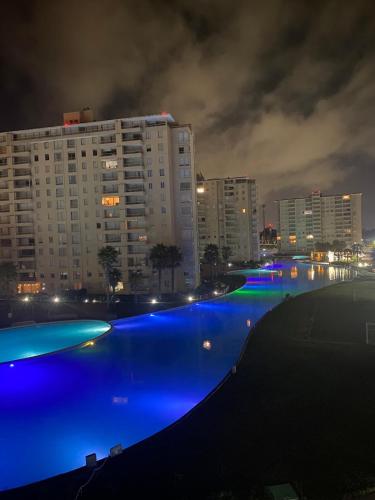a swimming pool with blue lights in a city at night at Amplio departamento en Condominio Laguna Vista Algarrobo in Algarrobo